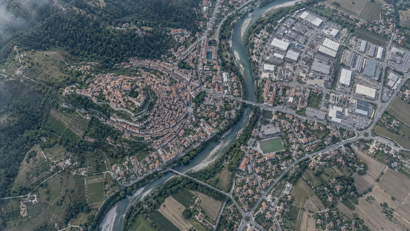 Vista aerea di una cittadina divisa da un fiume, tra centro storico, zona residenziale e area industriale